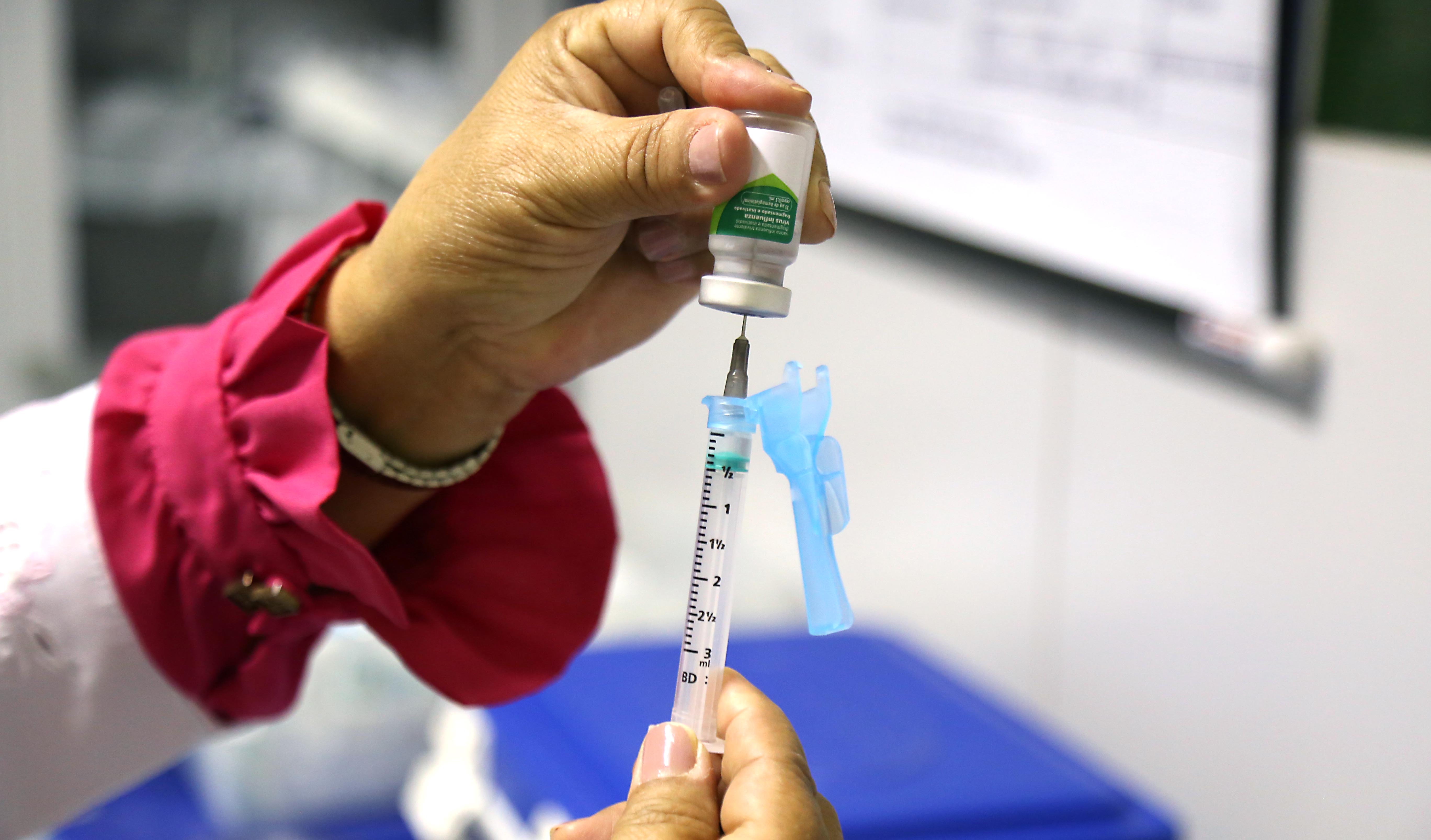 uma mão segura uma seringa de vacina
